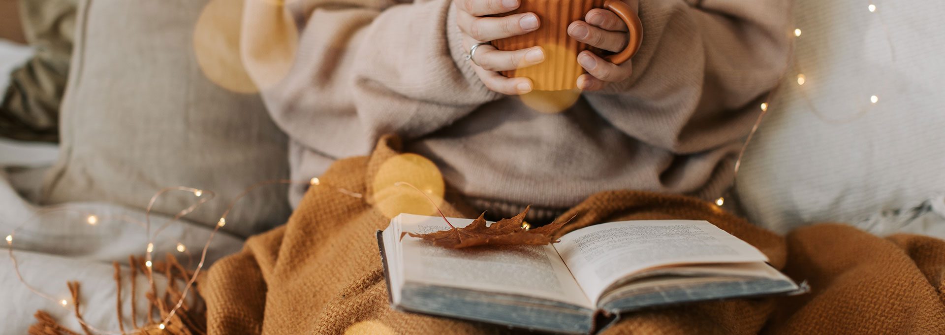 a person reading a book and holding a cup of coffee at The Wilder